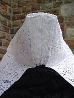 Achterkant van de trapezevormige muts. De achterkant is over de gehele lengte geplooid. 